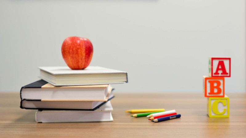 An apple on some books next to pencils