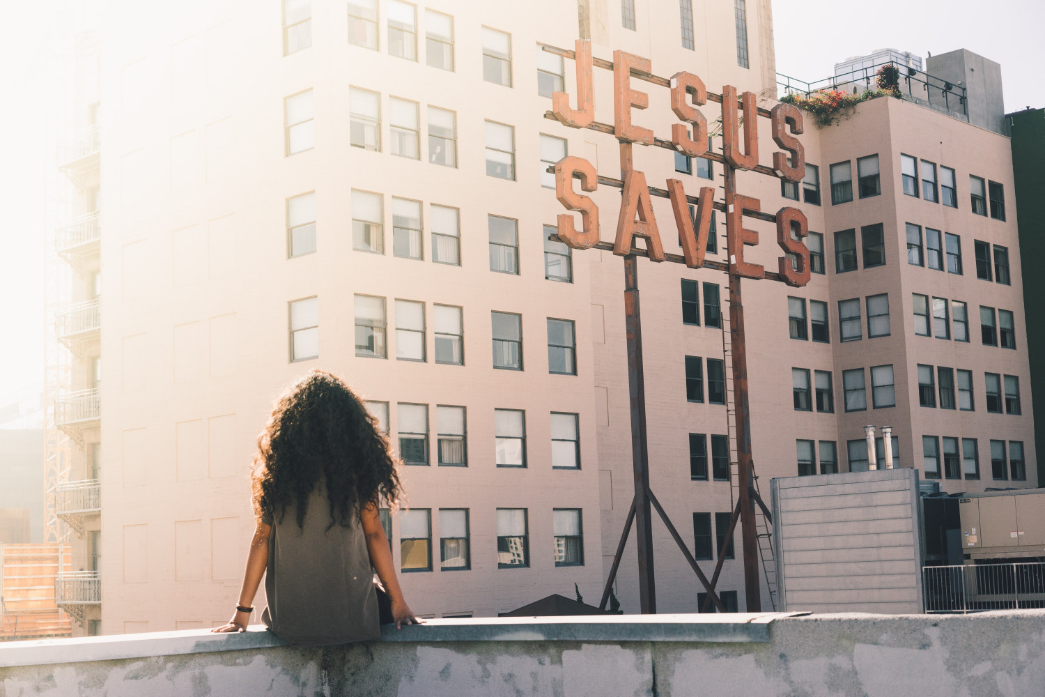 A person sat on a roof top looking at a flat block