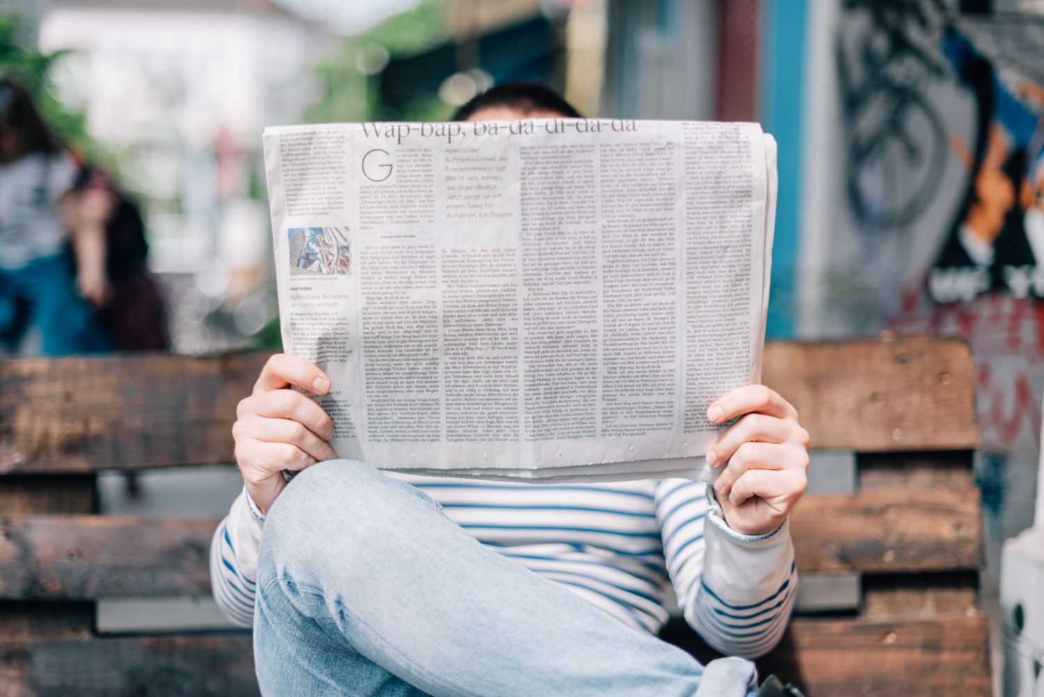 Person sat on a bench reading a newspaper