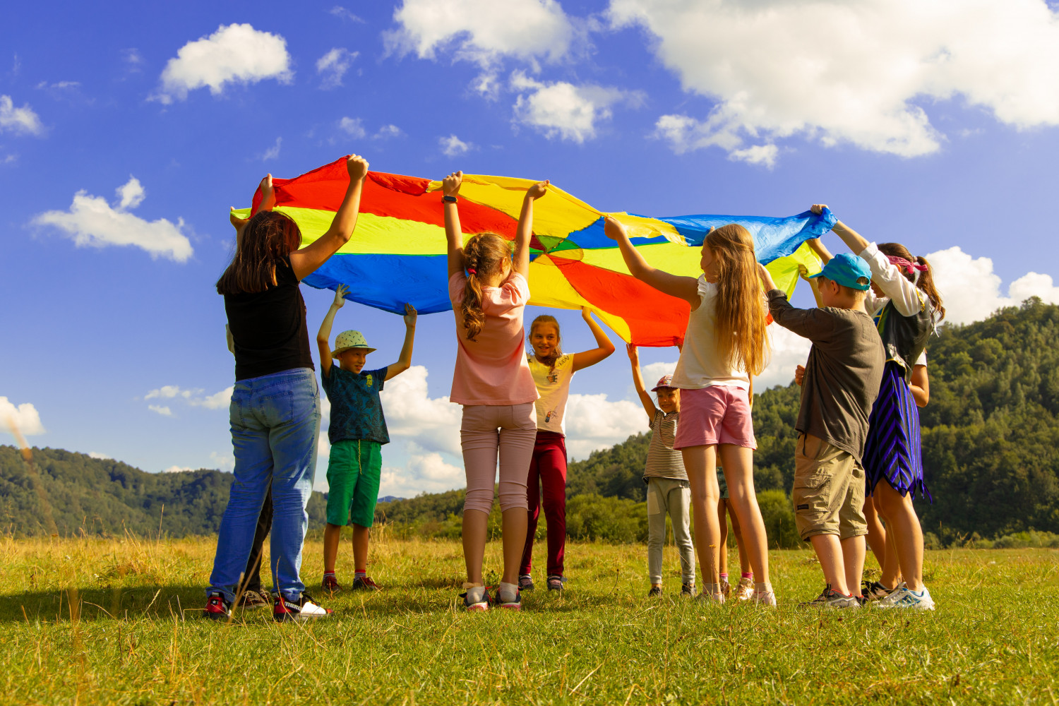 Children in a group waving an open parachute