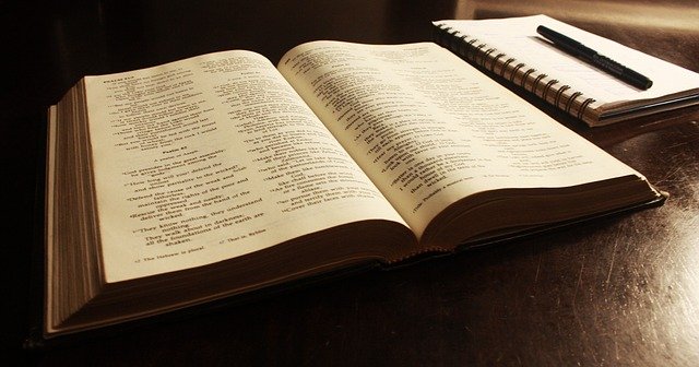 An open Bible next to a notebook and pen