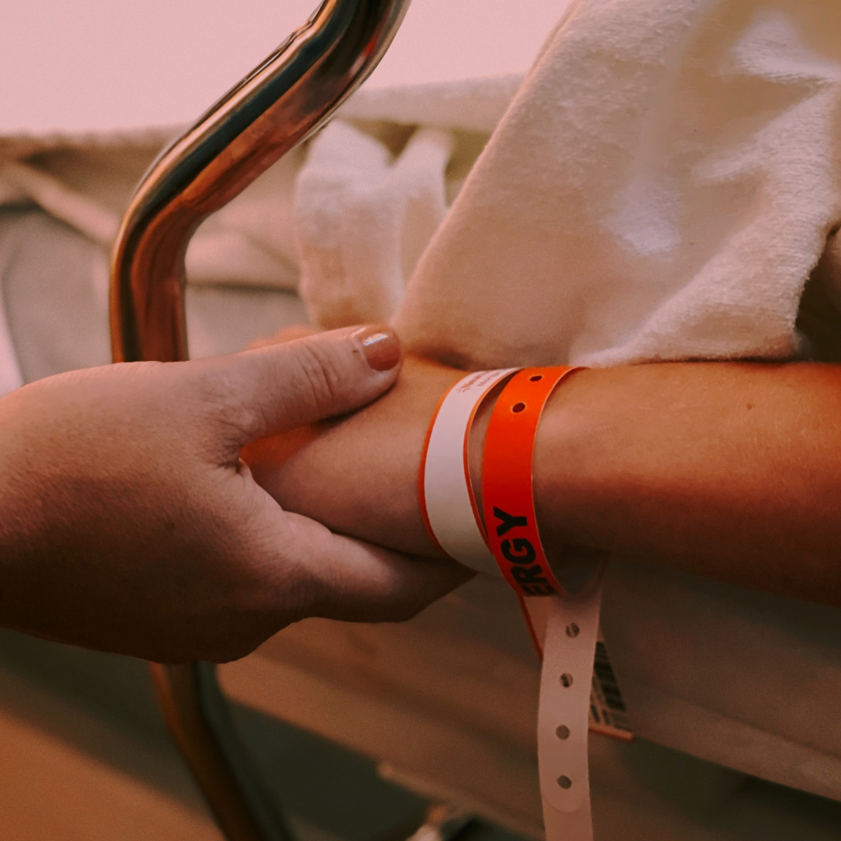 A person holding the hand of someone in hospital