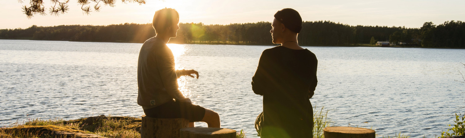 Two people talking by a lake