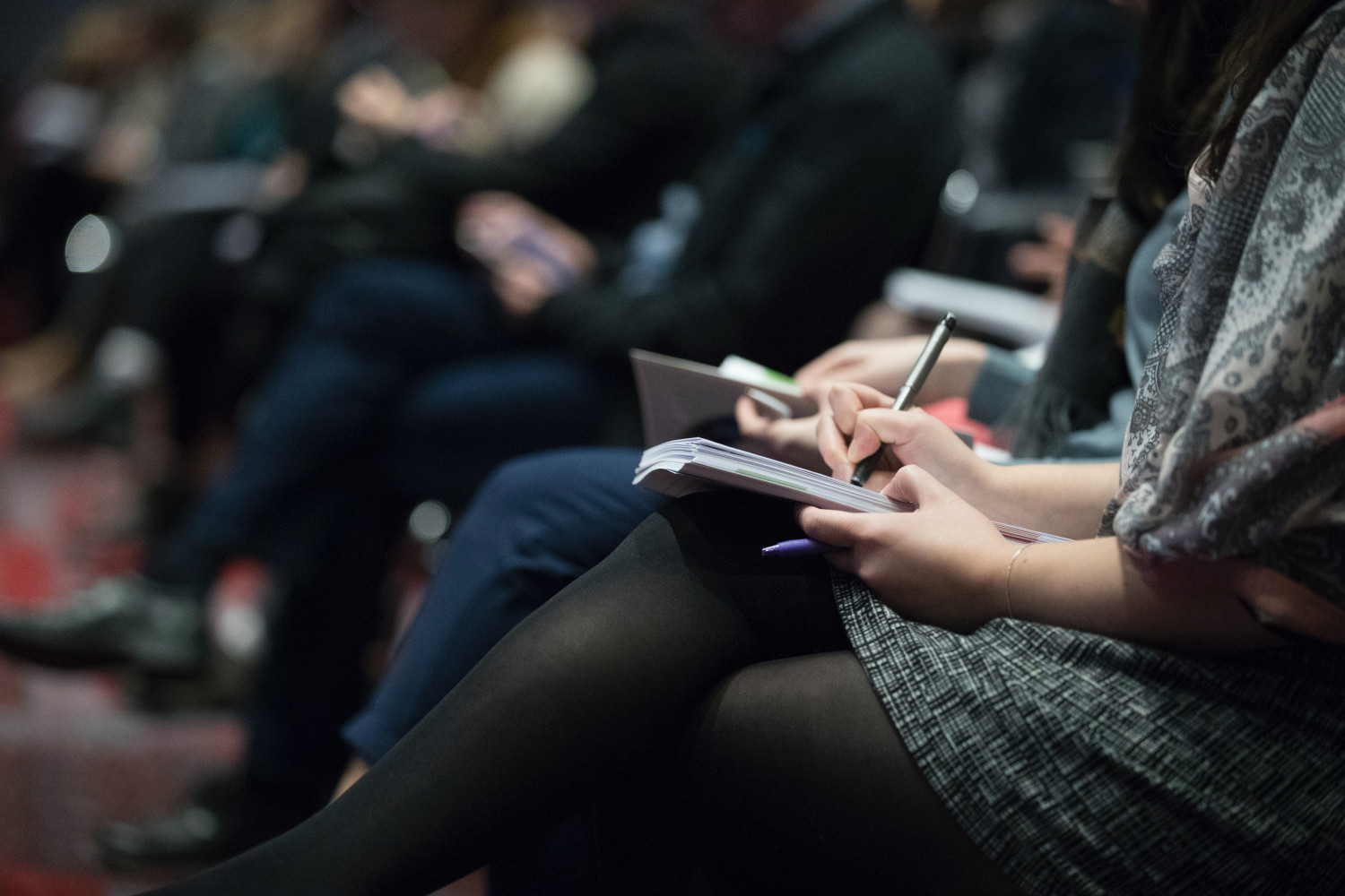 People sat in a line making notes in a notebook