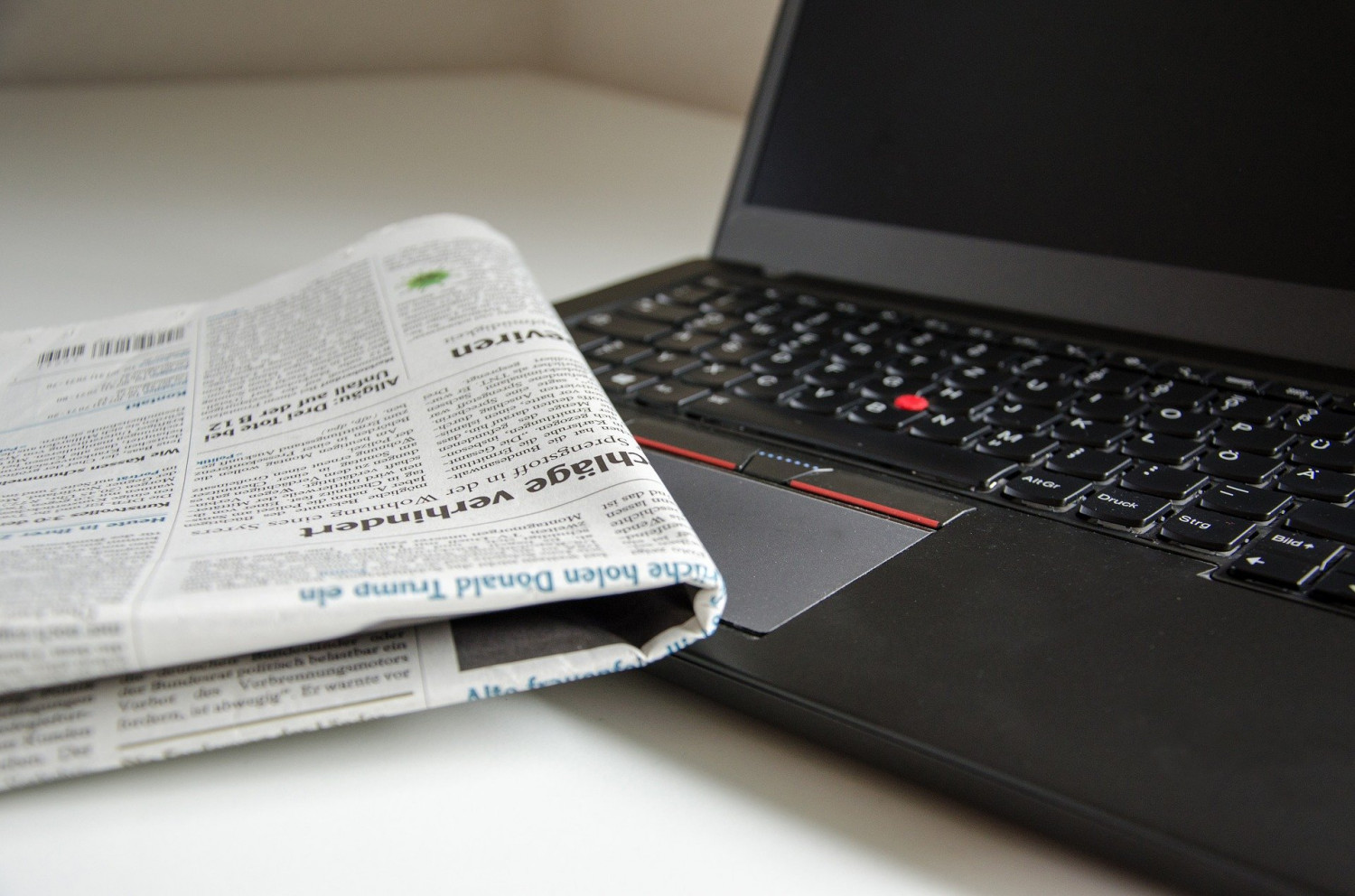 A folded up newspaper on top of a laptop