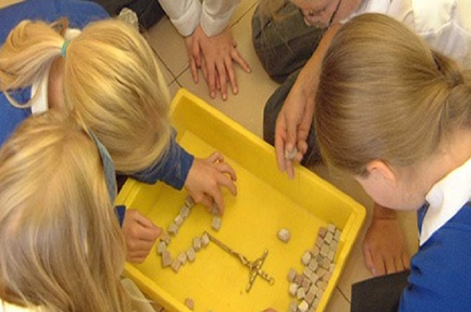 Children playing with a cross and pebbles in a lesson