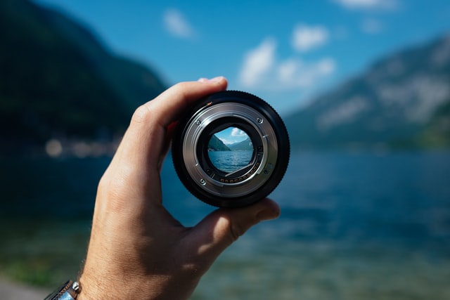 A person holding up a camera lens